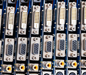 A close-up of several rows of computer graphic cards, showing multiple stacked ports including DVI connectors, VGA connectors, and S-Video connectors. The arrangement forms a grid-like pattern with the metallic connectors prominently displayed—an impressive lineup for any equipment finance project.